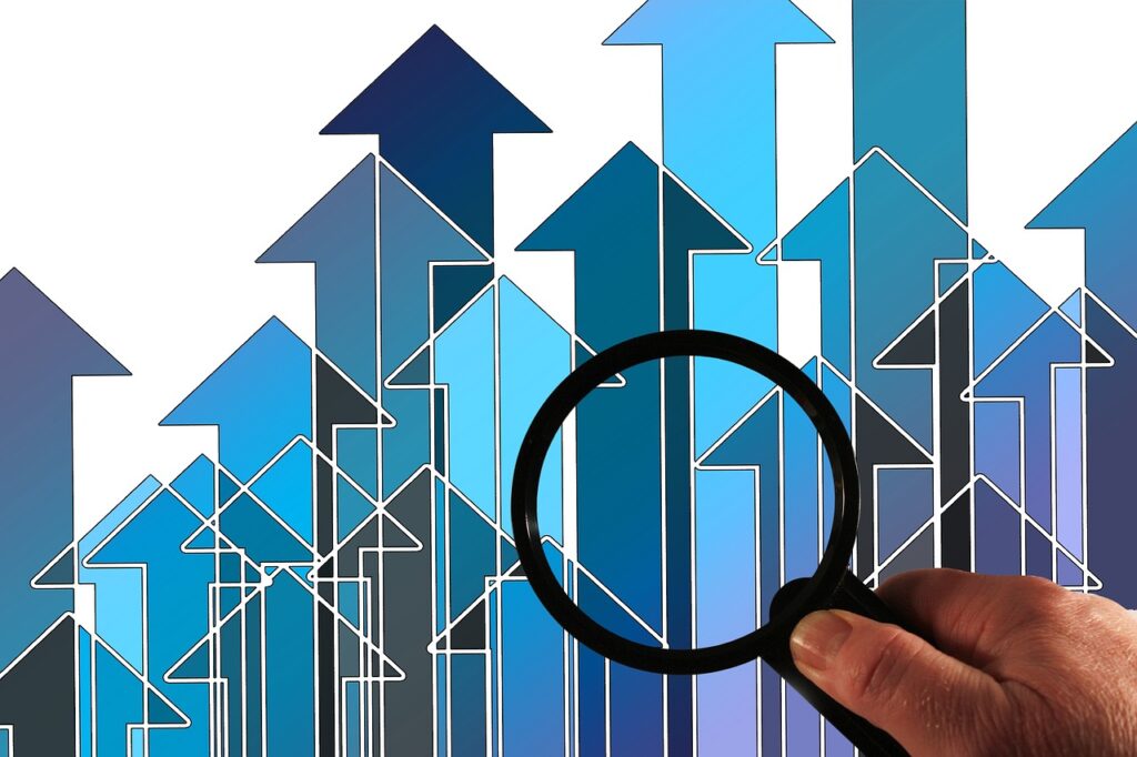 Main tenant une loupe sur un fond de flèches ascendantes symbolisant l'analyse et la croissance.